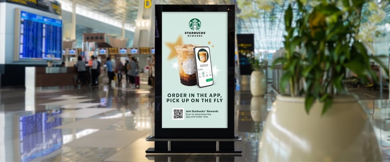 A DOOH screen showing a Starbucks ad in an airport