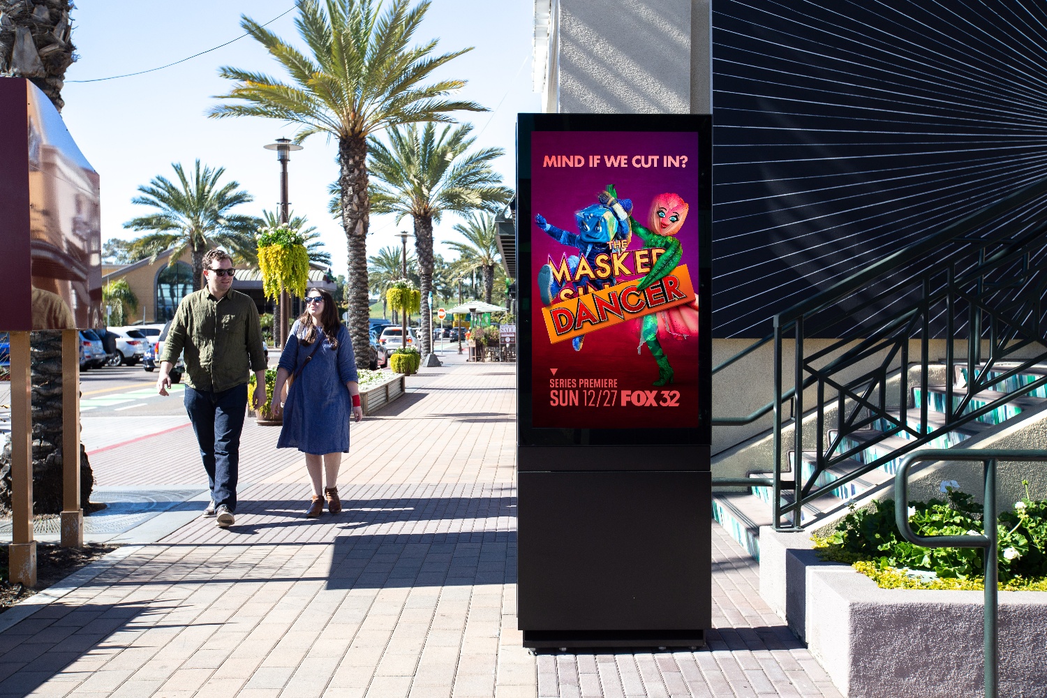 A DOOH screen shows a TV show ad