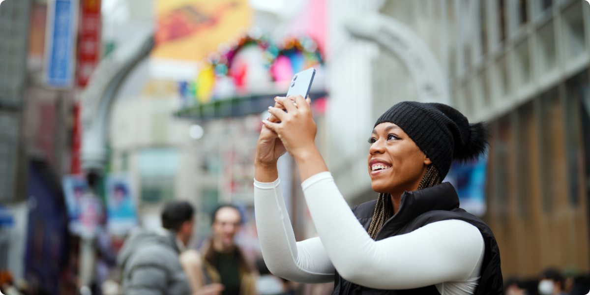 Image of a woman outside with her phone looking at out-of-home advertising