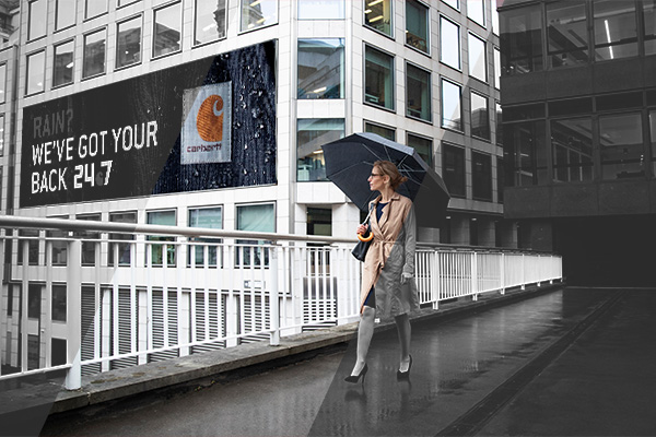 women walking in the rain and seeing a programmatic DOOH ad for rain coats